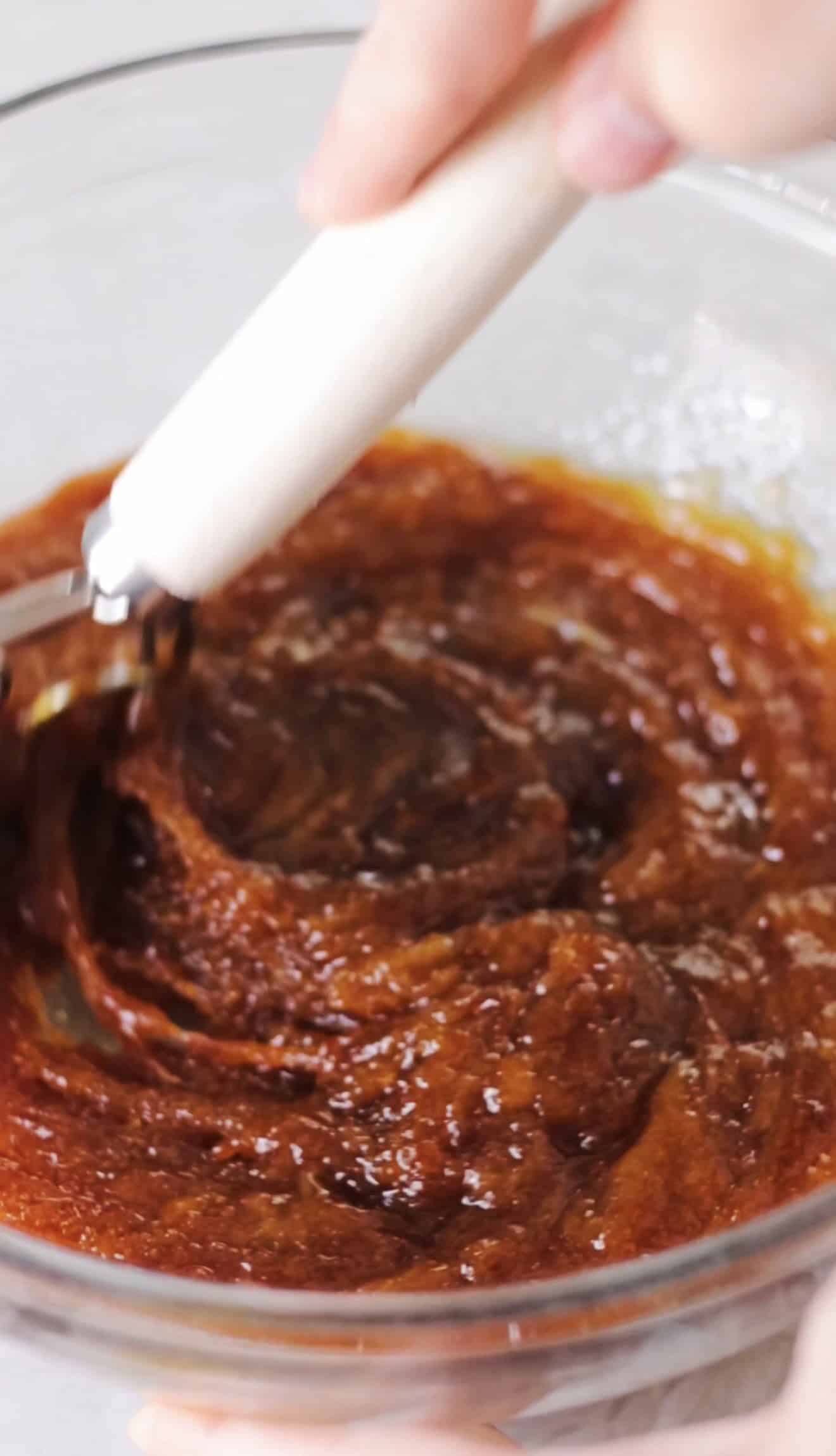 Glass mixing bowl of molasses, oil, sugar and egg mixed together.