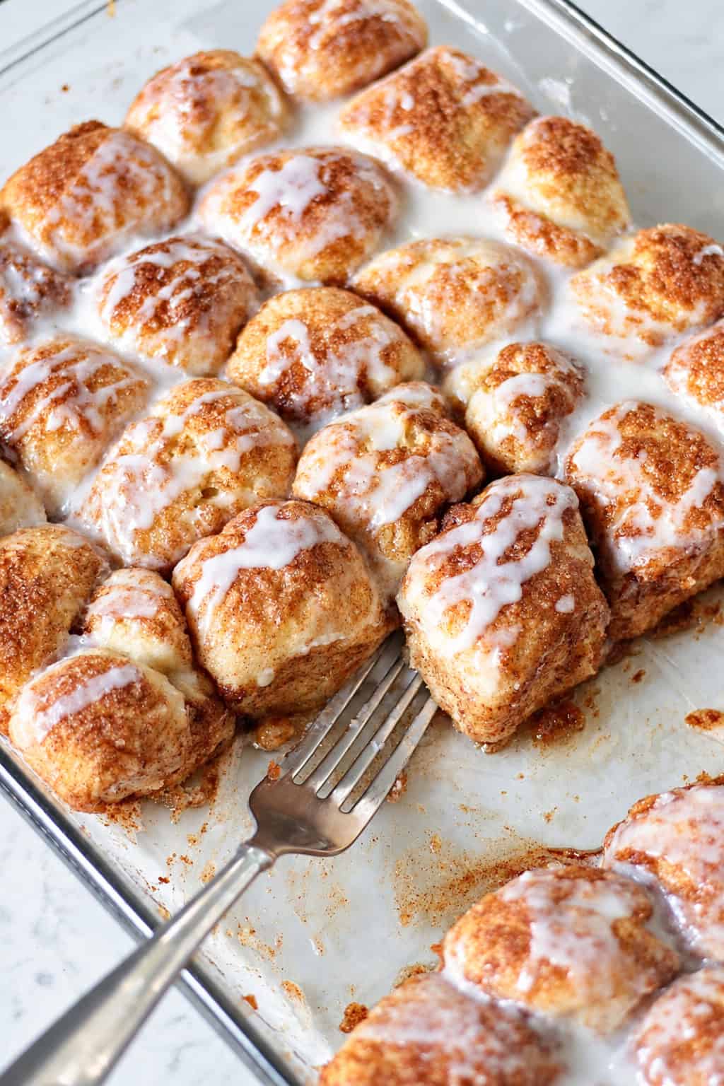 Baking dish of cinnamon roll bites with fork.