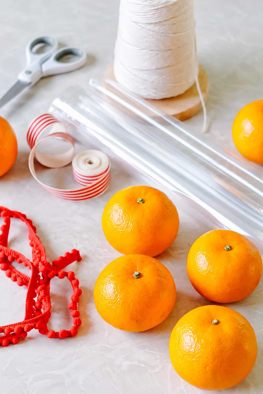 Clementines, cellophane, ribbon and twine on table.
