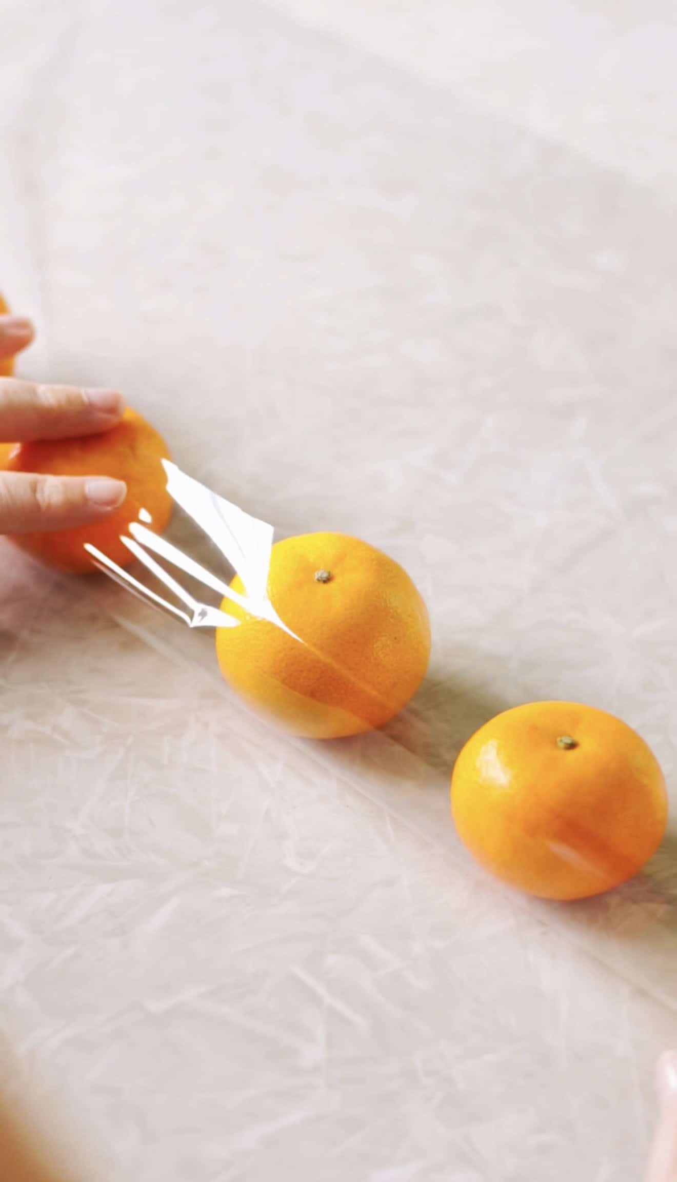 Hands rolling clementines in cellophane.