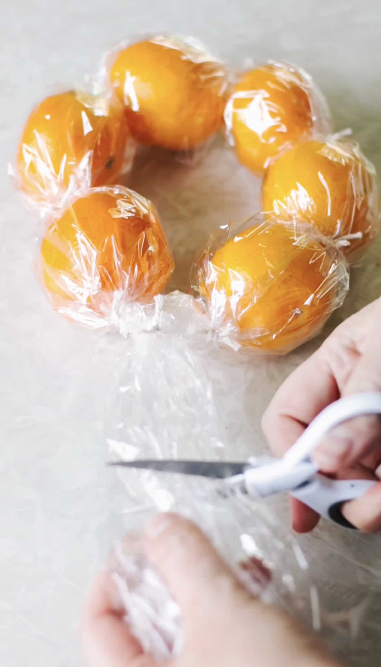 Hands tying ends of clementine wreath together.