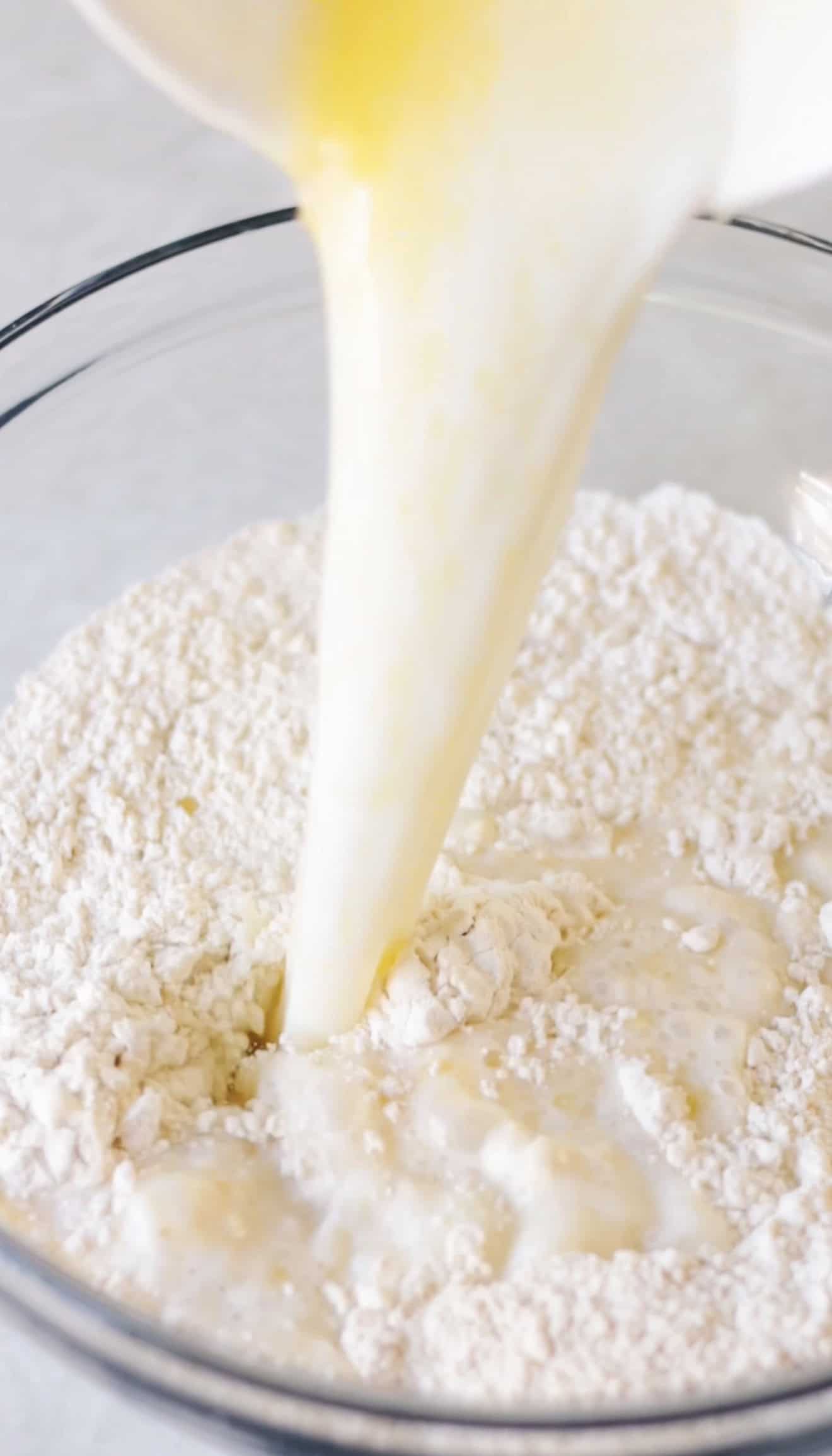 Wet ingredients poured into glass mixing bowl of flour.