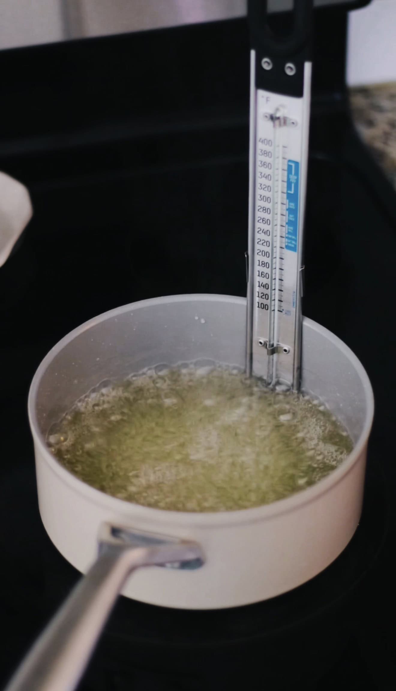 Candy thermometer in pan of hot sugar mixture.