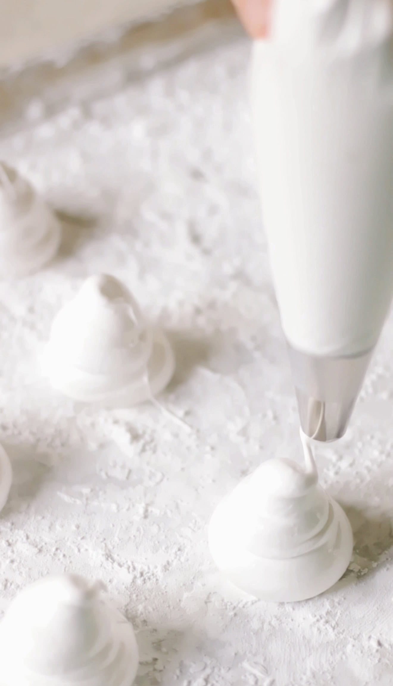 Ghost marshmallows being piped onto baking sheet.