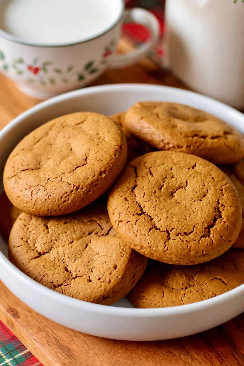 Gingerbread cookies on white platter with mug of milk in background. 
