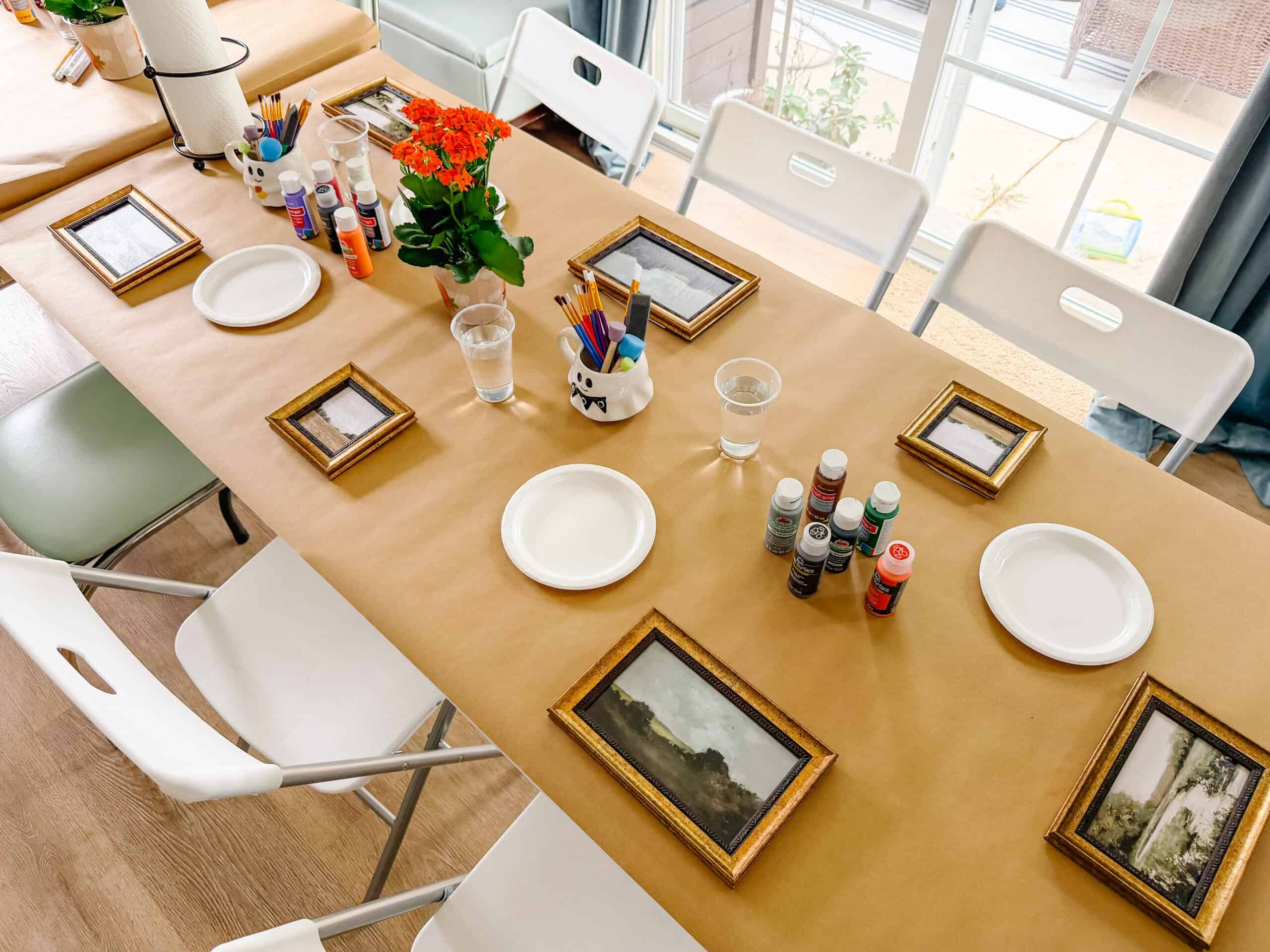 Table covered with brown Kraft paper, plates, supplies and frames.