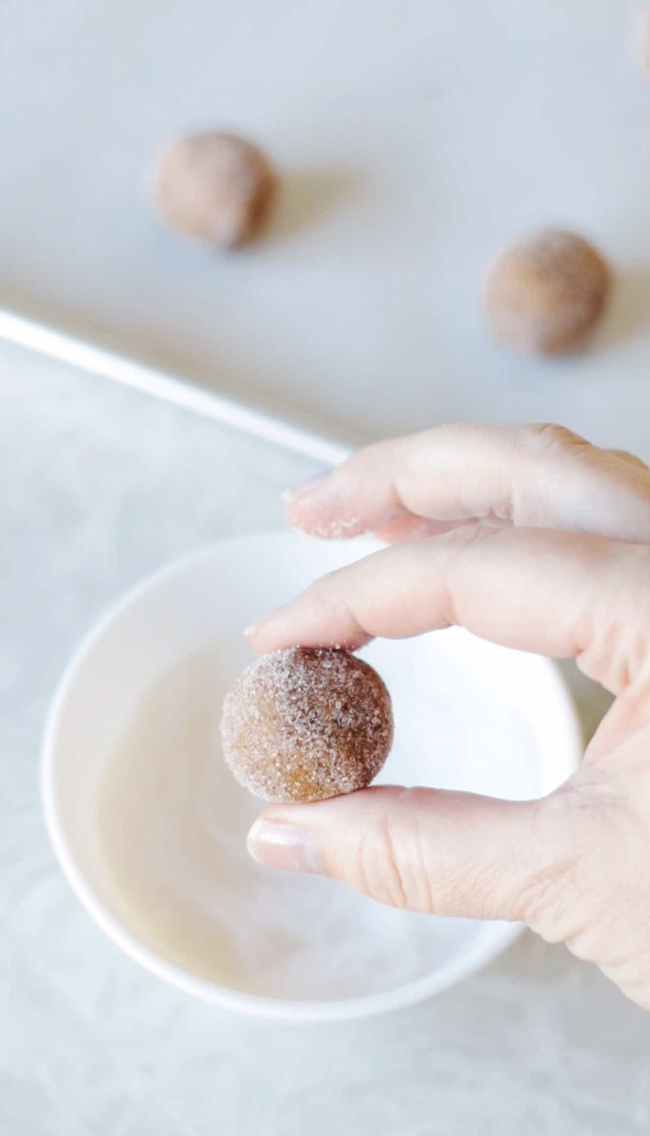 Hand holding sugar coated cookie dough ball.