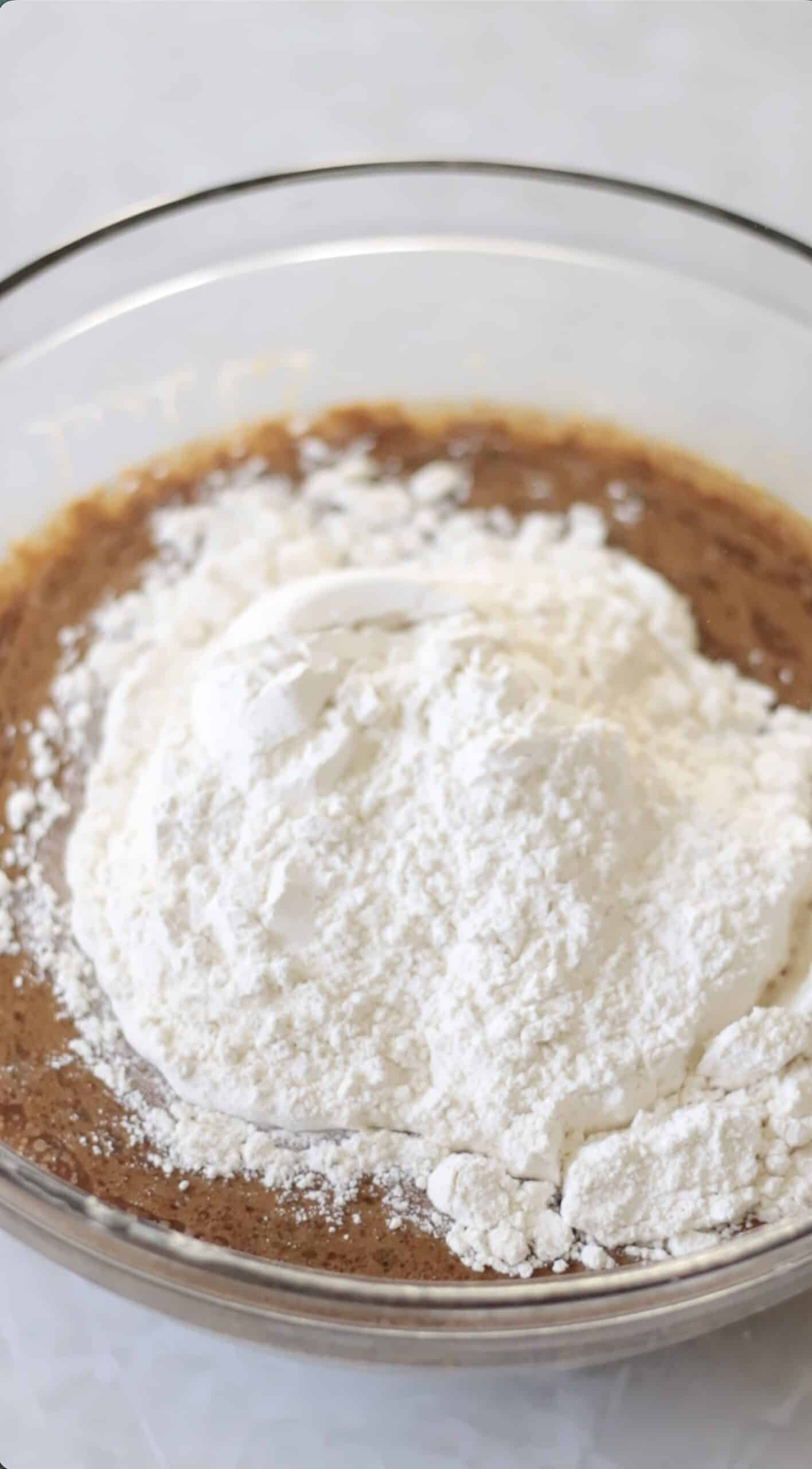 Bowl of wet ingredients and flour poured on top.