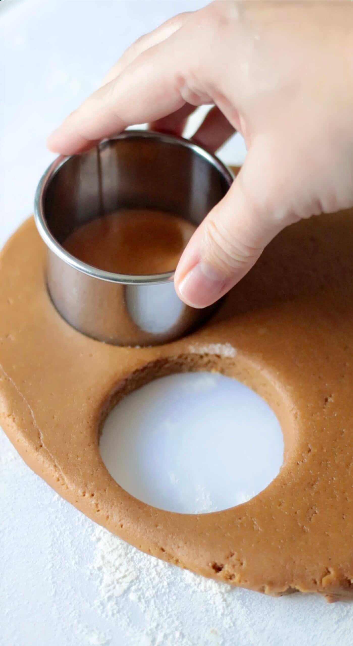 Hand cutting out cookie shapes from dough with a cookie cutter.